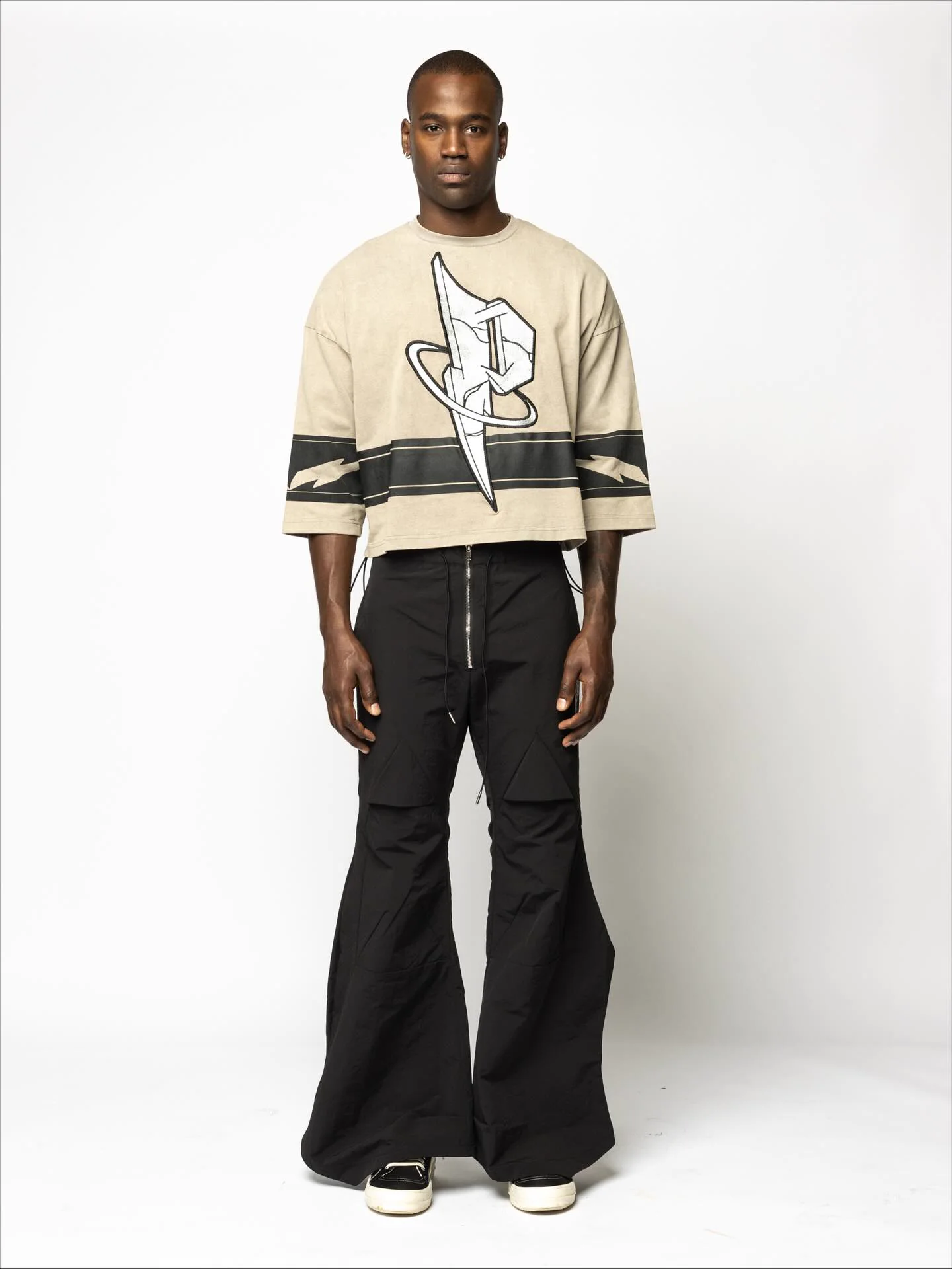 Model wearing a cream PSRVE graphic top with black flare pants